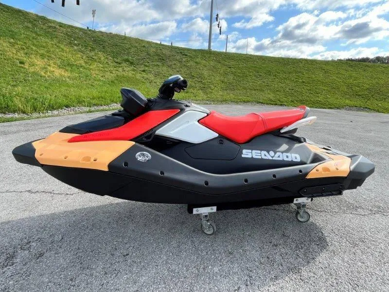 Slide: The Image of 2024 Sea-Doo Spark jet ski with red seat, parked on pavement under cloudy sky. - 22