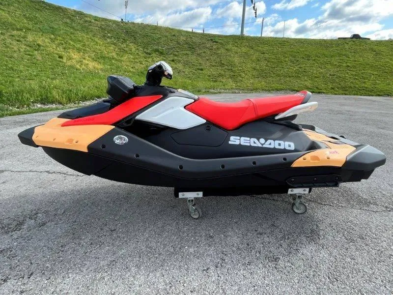 Slide: The Image of 2024 Sea-Doo Spark jet ski with red seat, parked on pavement. - 3