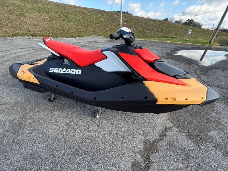 Slide: The Image of 2024 Sea-Doo Spark jet ski with red seat and black body on pavement. - 2