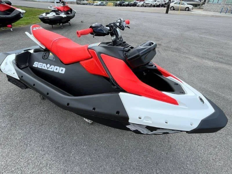 Slide: The Image of 2024 Sea-Doo Spark Trixx jet ski, red and black design, parked on pavement. - 12