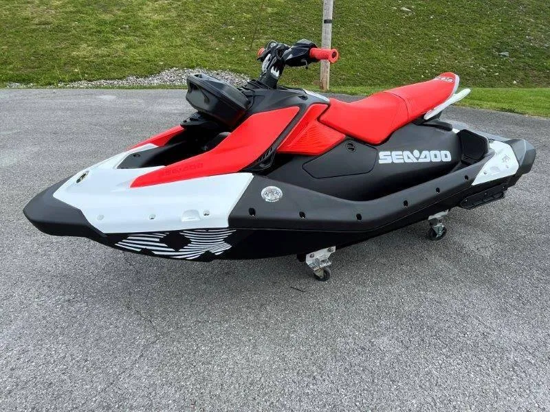 Slide: The Image of 2024 Sea-Doo Spark Trixx jet ski, red and black, parked on pavement. - 4