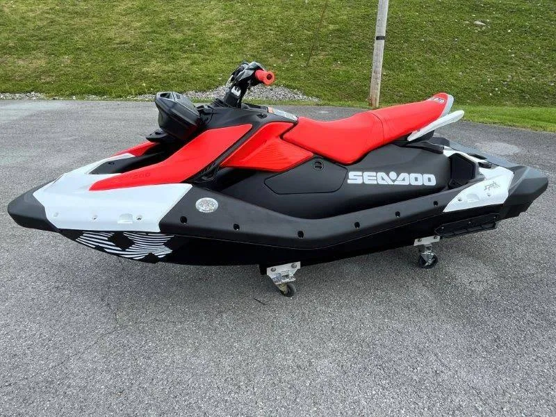 Slide: The Image of 2024 Sea-Doo Spark Trixx jet ski, red and black, parked on pavement. - 7
