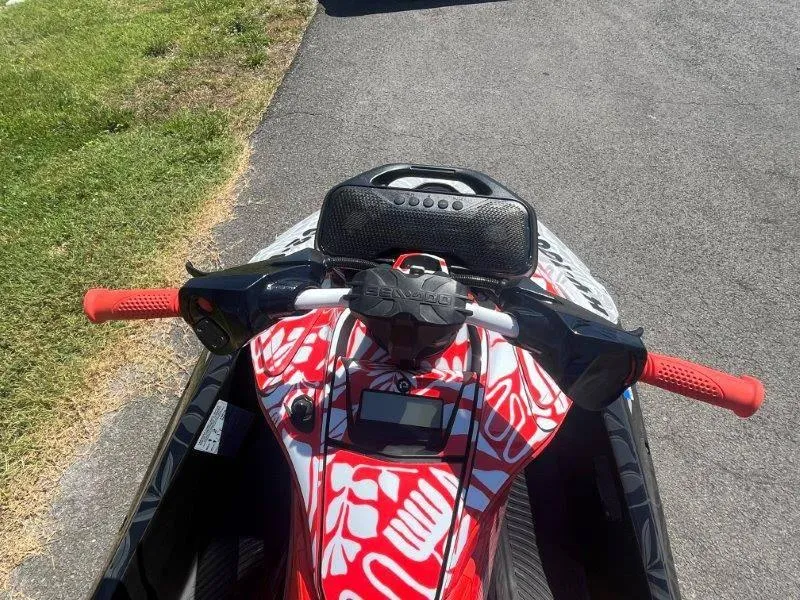 Slide: The Image of 2024 Sea-Doo Spark 1UP Trixx 90 Sound, vibrant red design, parked on pavement. - 23