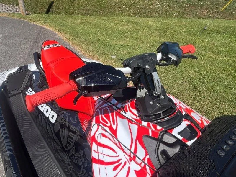 Slide: The Image of 2024 Sea-Doo Spark 1UP Trixx 90 Sound, vibrant red and white design, parked on grass. - 24