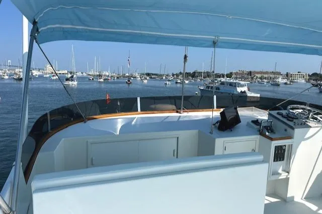 Slide: The Image of 1980 Huckins Sports Cruiser on calm waters, featuring a spacious deck and marina view. - 14