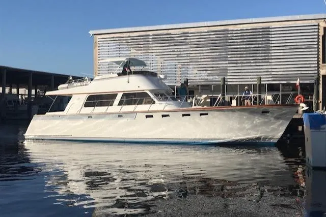 Slide: The Image of 1980 Huckins Sports Cruiser yacht docked at marina, reflecting on calm water. - 2
