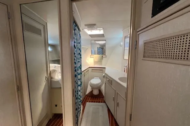 Slide: The Image of 1980 Huckins Sports Cruiser bathroom with shower, toilet, and sink, featuring wood flooring. - 26