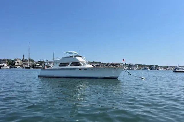 Slide: The Image of 1980 Huckins Sports Cruiser yacht anchored in calm waters under a clear blue sky. - 3