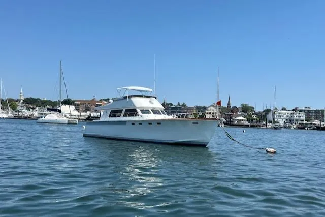 Slide: The Image of 1980 Huckins Sports Cruiser yacht anchored in a scenic harbor. - 5