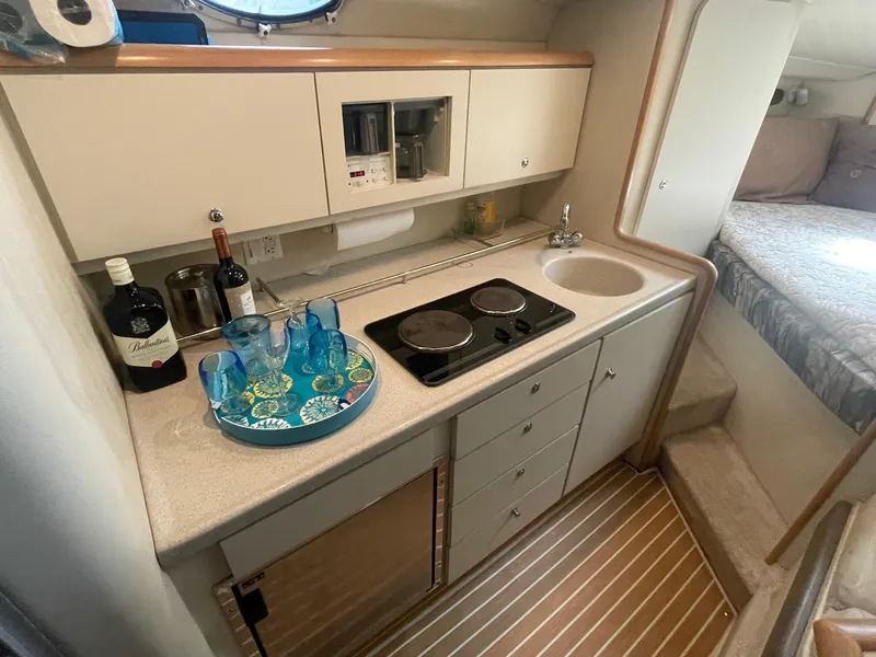 Slide: The Image of 1997 Wellcraft 3200 Martinique yacht kitchen with stove, sink, and countertop accessories. - 7