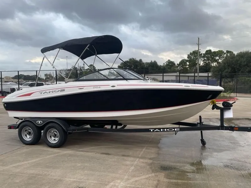 Slide: The Image of 2024 Tahoe 210 Si boat on trailer, parked outdoors under cloudy sky. - 1