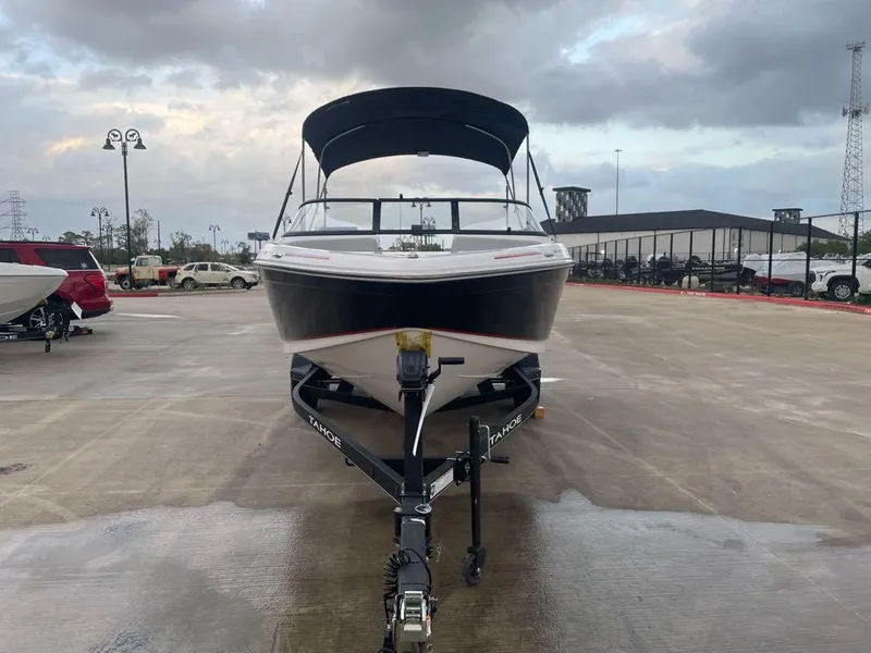 Slide: The Image of 2024 Tahoe 210 Si boat on trailer in parking lot under cloudy sky. - 2