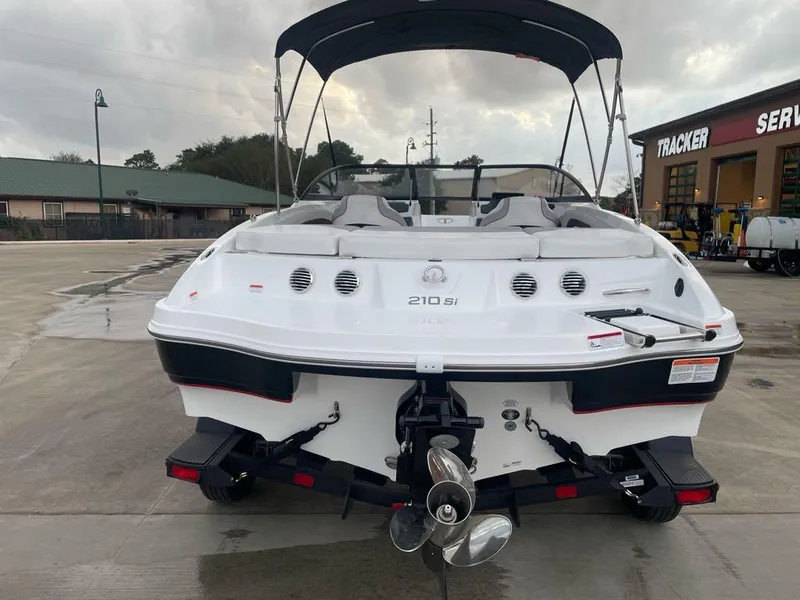 Slide: The Image of 2024 Tahoe 210 Si boat, rear view, parked outdoors, overcast sky. - 3
