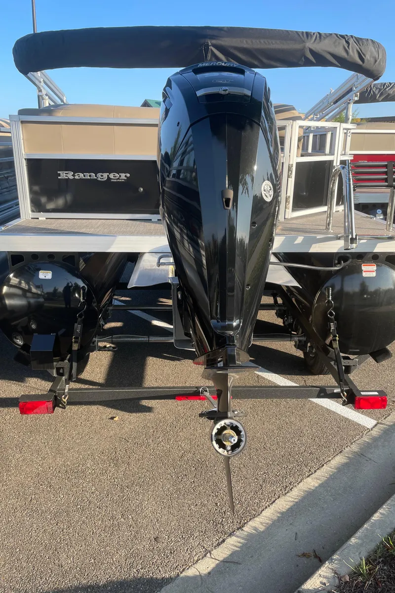 Slide: The Image of 2024 Ranger Reata 200C boat with powerful outboard motor, parked on pavement. - 5