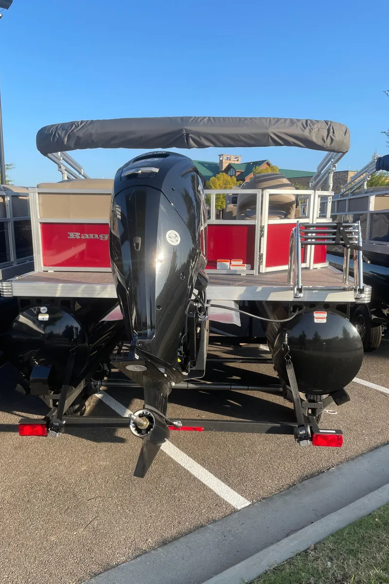 Slide: The Image of 2024 Ranger Reata 200C pontoon boat with outboard motor, parked on pavement. - 6