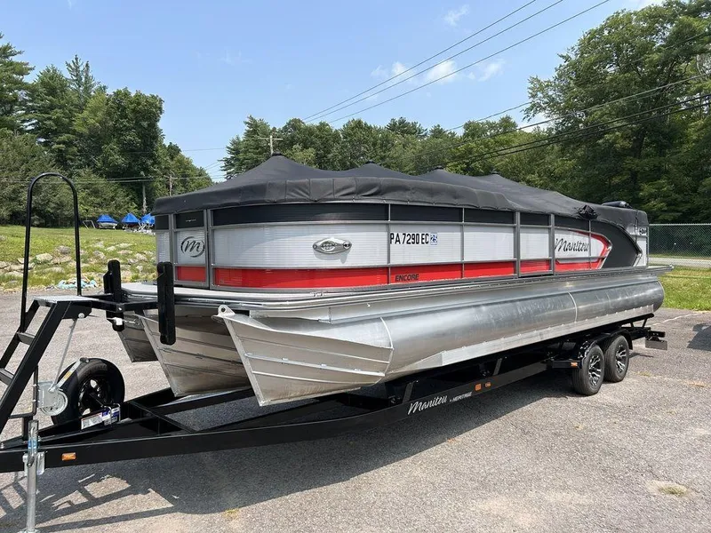 The Image of 2022 Manitou Encore 25 pontoon boat on trailer, covered, parked outdoors. - 1