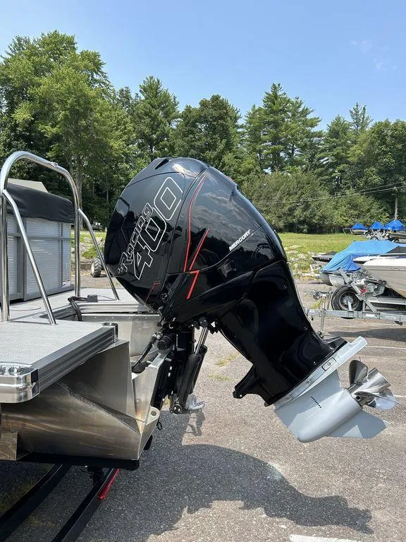 Slide: The Image of 2022 Manitou Encore 25 with powerful outboard motor, parked outdoors. - 11