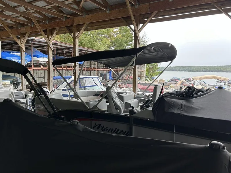 Slide: The Image of 2022 Manitou Encore 25 pontoon boat in covered dock, surrounded by other boats. - 13