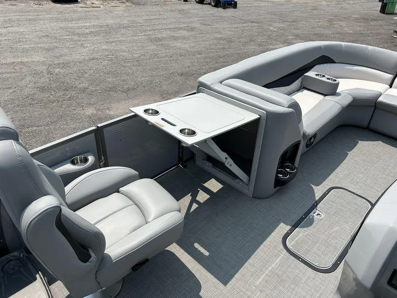 Slide: The Image of 2022 Manitou Encore 25 boat interior with gray seating and foldable table. - 15
