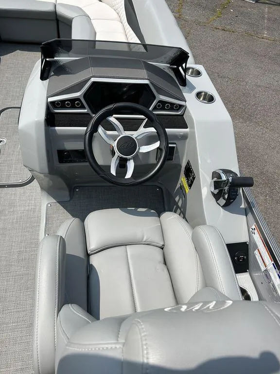 Slide: The Image of 2022 Manitou Encore 25 boat interior with modern steering console and seating. - 16