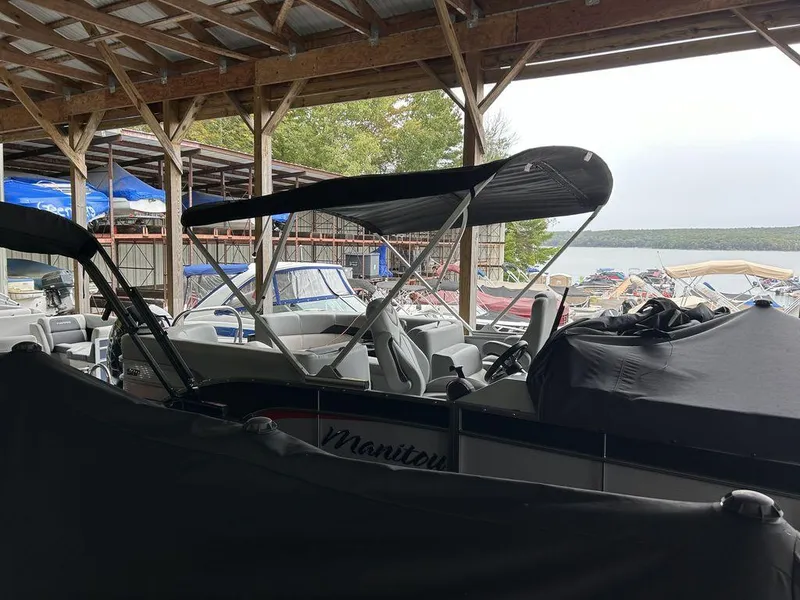 Slide: The Image of 2022 Manitou Encore 25 pontoon boat in covered dock, surrounded by other boats. - 19