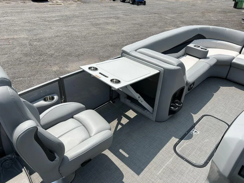 Slide: The Image of 2022 Manitou Encore 25 pontoon boat interior with gray seating and foldable table. - 6