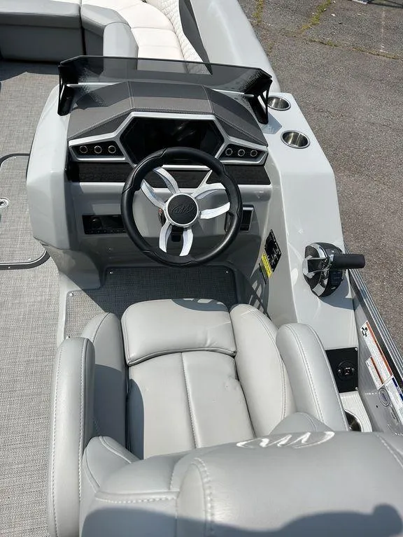 Slide: The Image of 2022 Manitou Encore 25 boat dashboard with steering wheel and seating. - 7