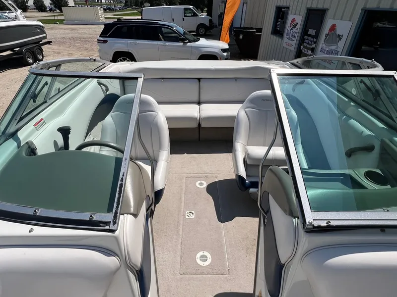 Slide: The Image of 2001 Crownline 192 BR boat interior with white seating and windshield, parked outdoors. - 8