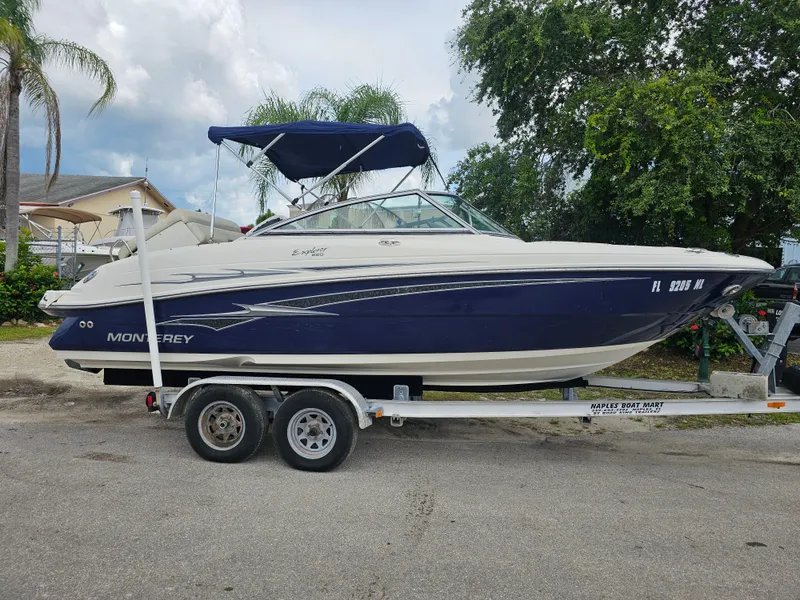 Slide: The Image of 2007 Monterey 220 EX boat on trailer, parked outdoors with trees and houses in the background. - 2