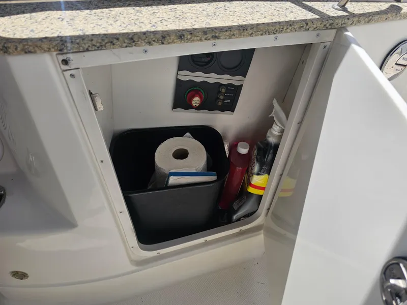 Slide: The Image of Open storage compartment in 2007 Monterey 220 EX boat with cleaning supplies and paper towels. - 21