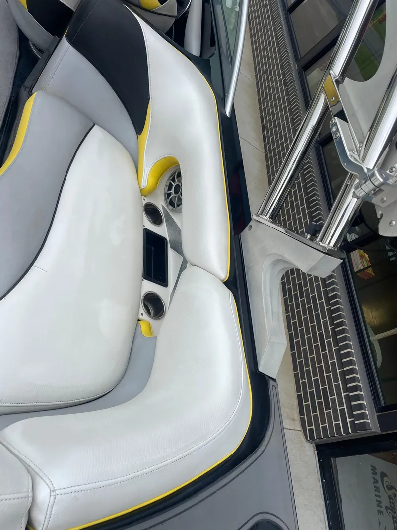 Slide: The Image of 2013 MB F21 Tomcat boat interior with white and yellow seating, cup holders, and speaker. - 23