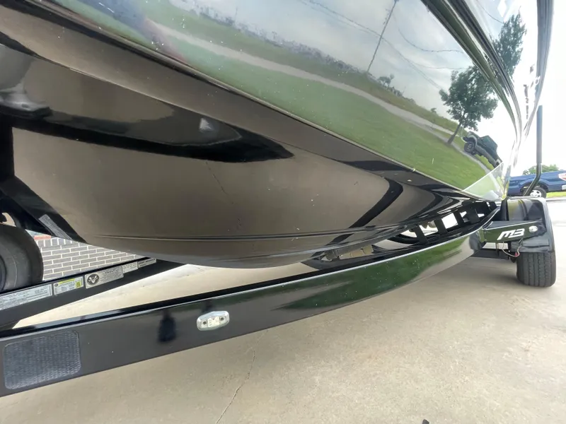 Slide: The Image of 2013 MB F21 Tomcat boat on trailer, underside view, parked outdoors. - 24