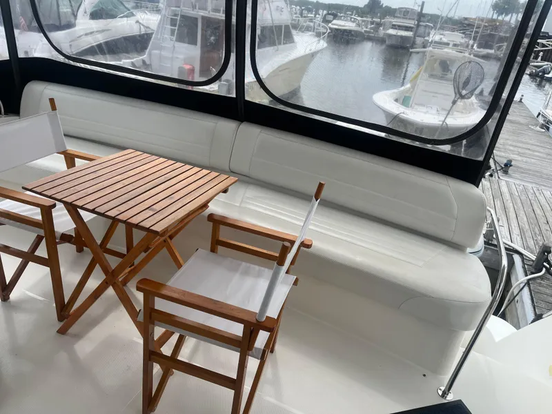 Slide: The Image of 2006 Carver 430 Cockpit Motor Yacht interior with wooden table and chairs, marina view. - 19