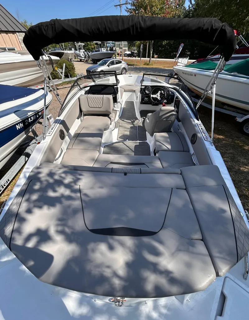 Slide: The Image of 2024 Glastron GX 215 boat with spacious seating and canopy, parked outdoors. - 10