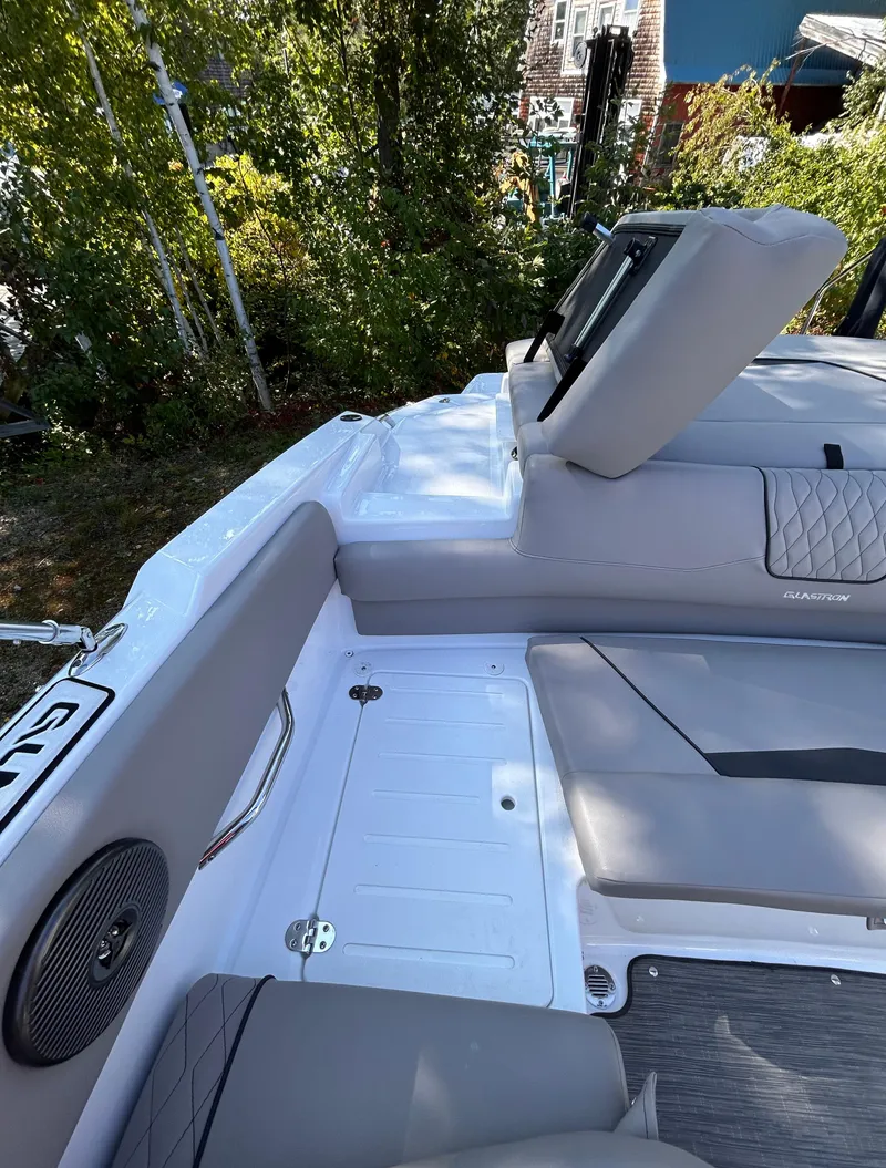 Slide: The Image of 2024 Glastron GX 215 boat interior with gray seating and speaker detail. - 13