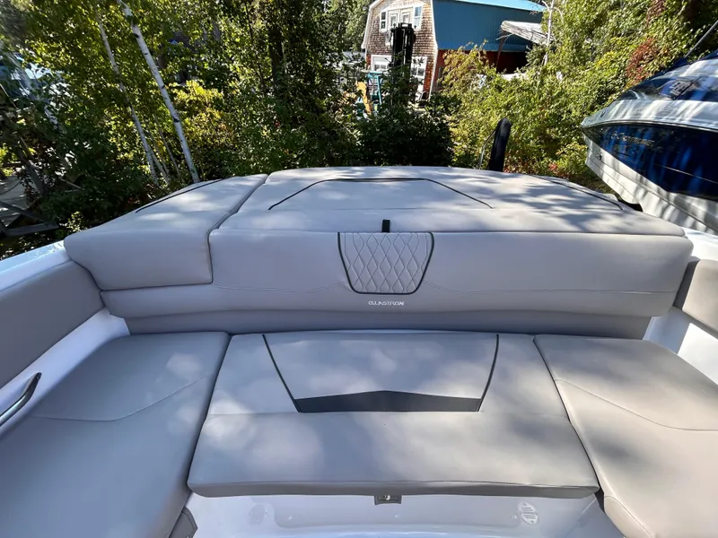 Slide: The Image of 2024 Glastron GX 215 boat with sleek, cushioned seating in a lush outdoor setting. - 16