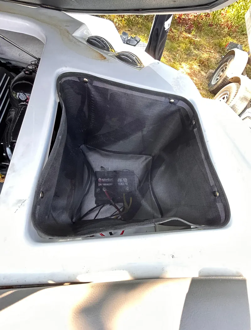 Slide: The Image of 2024 Glastron GX 215 boat storage compartment with black mesh liner. - 21