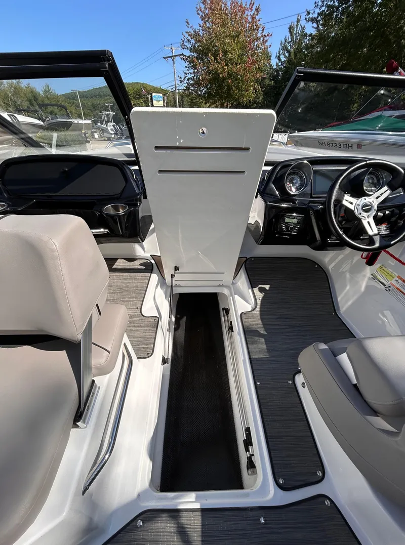Slide: The Image of 2024 Glastron GX 215 boat interior with open storage compartment and steering wheel. - 31