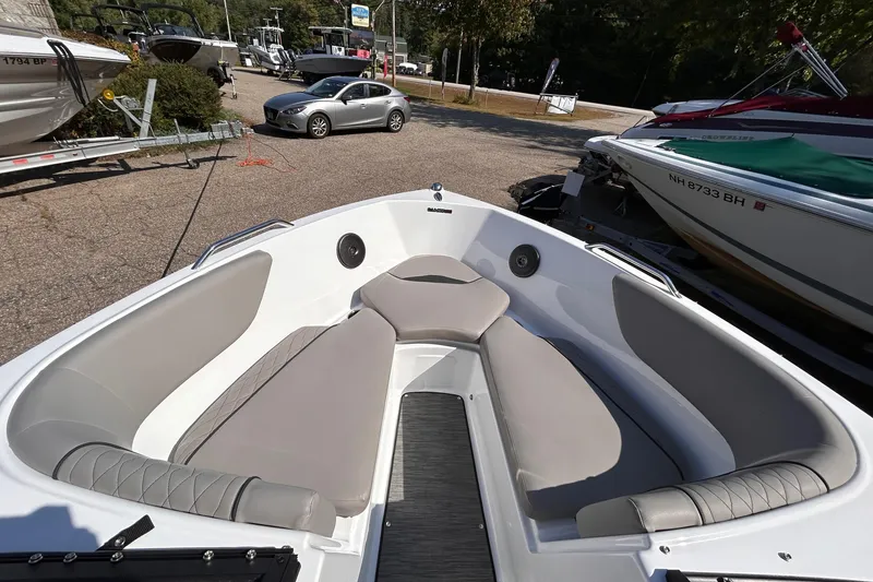 Slide: The Image of 2024 Glastron GX 215 boat interior with cushioned seating, parked outdoors. - 36