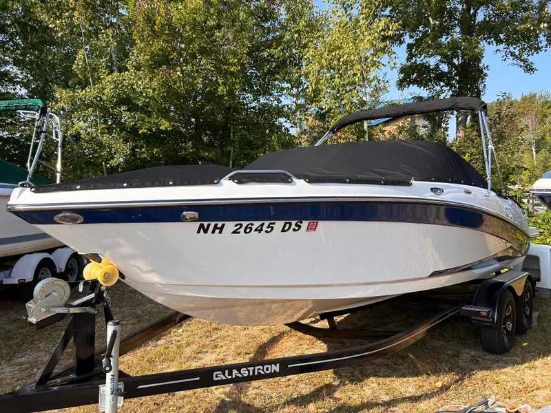 Slide: The Image of 2024 Glastron GX 215 boat on trailer, covered, surrounded by trees. - 4