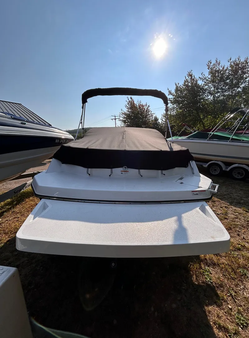 Slide: The Image of 2024 Glastron GX 215 boat with cover, parked outdoors under sunny sky. - 5