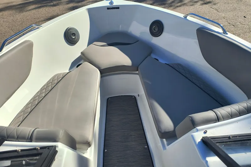 Slide: The Image of 2024 Glastron GX 215 boat interior with cushioned seating and speakers. - 15