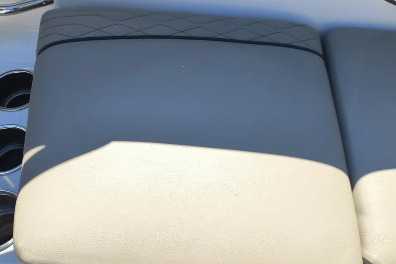 Slide: The Image of 2024 Glastron GX 215 boat seat with gray and beige upholstery, featuring cup holders. - 24