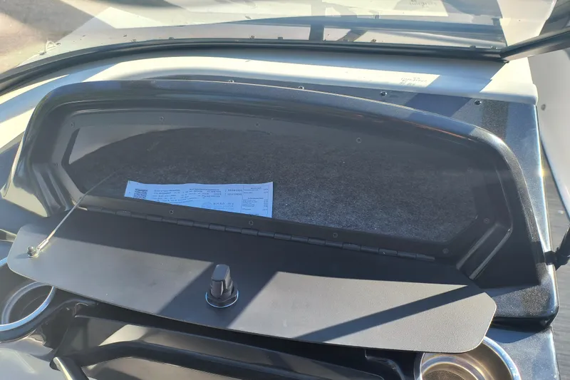 Slide: The Image of 2024 Glastron GX 215 boat dashboard with open glove compartment and visible document. - 6