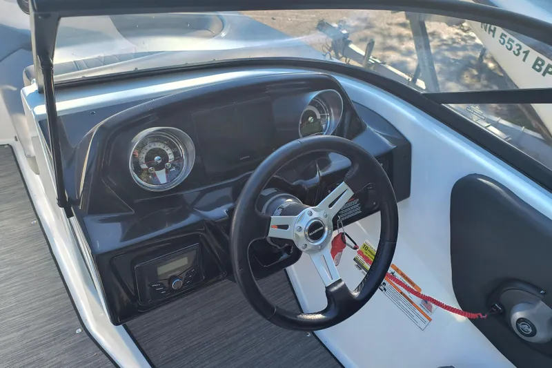 Slide: The Image of 2024 Glastron GX 215 boat dashboard with steering wheel and gauges. - 8