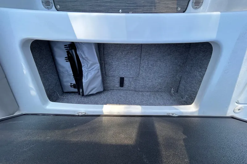 Slide: The Image of 2024 Glastron GX 215 boat storage compartment with gray interior and folded cover. - 23