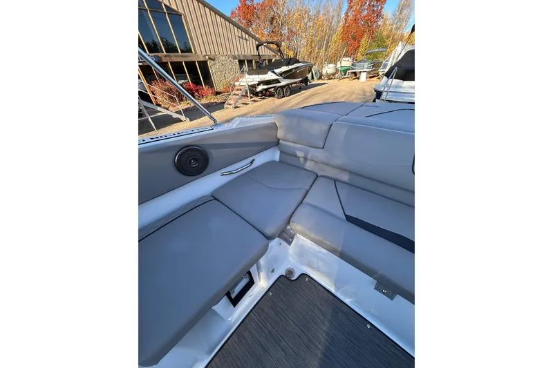 Slide: The Image of 2024 Glastron GX 215 boat interior with gray seating and outdoor setting. - 24