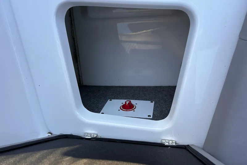 Slide: The Image of 2024 Glastron GX 215 boat storage compartment with red switch on carpeted floor. - 26