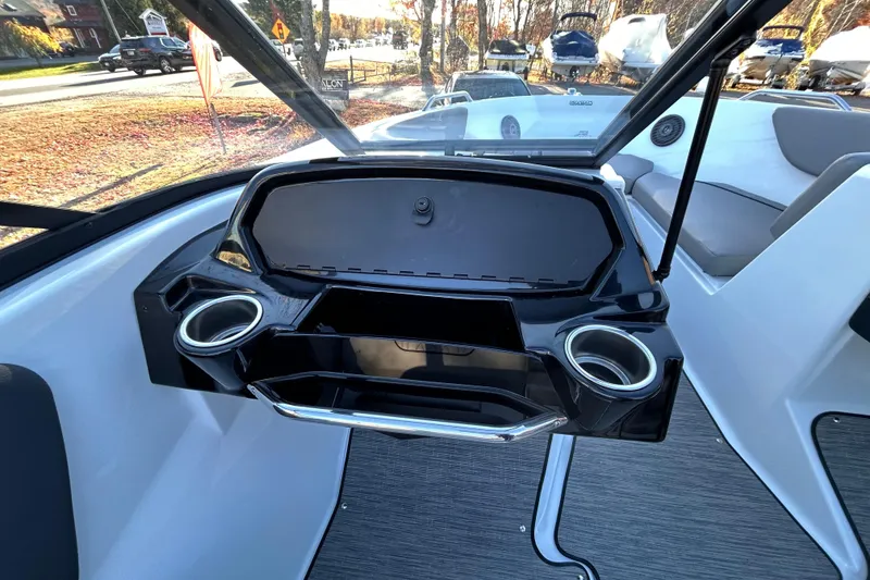 Slide: The Image of 2024 Glastron GX 215 boat dashboard with cup holders and storage compartment. - 32