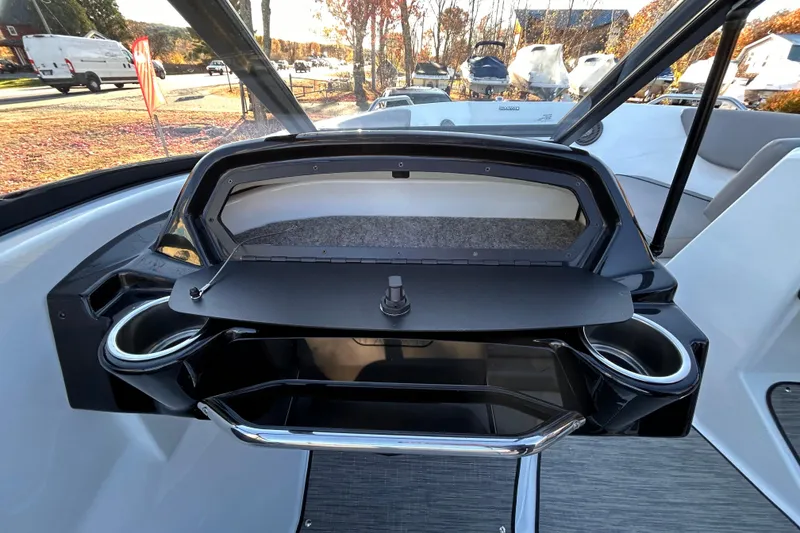 Slide: The Image of 2024 Glastron GX 215 boat dashboard with open glove compartment and cup holders. - 33